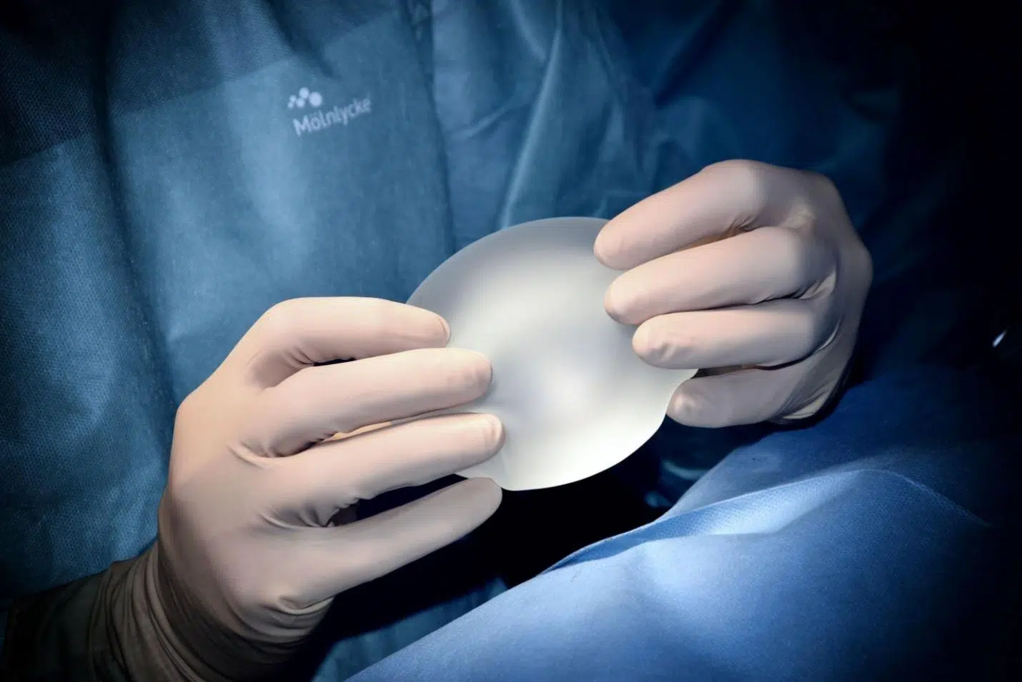 A surgeon holding a breast implant