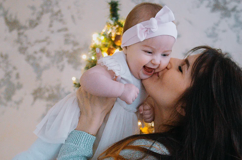 mother kissing child near christmas tree
