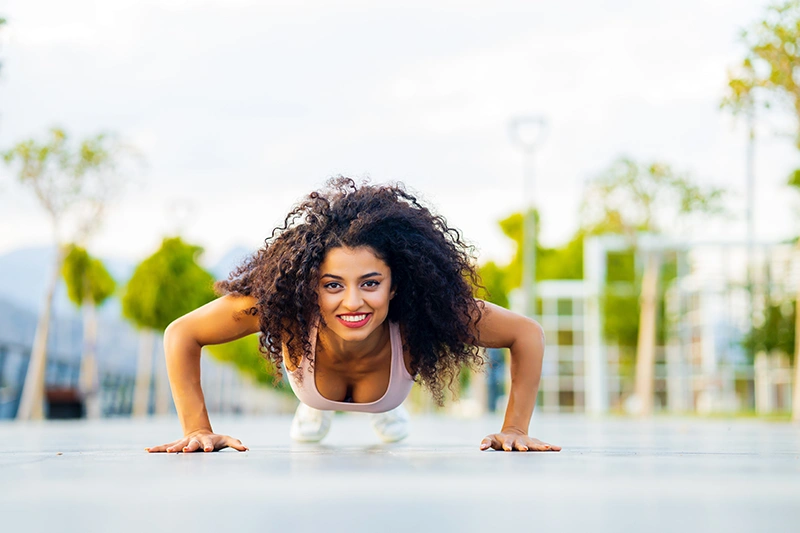 Woman performing push-up to target chest muscles for natural breast reduction