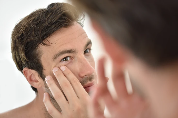 man examining under-eye area before cosmetic surgery