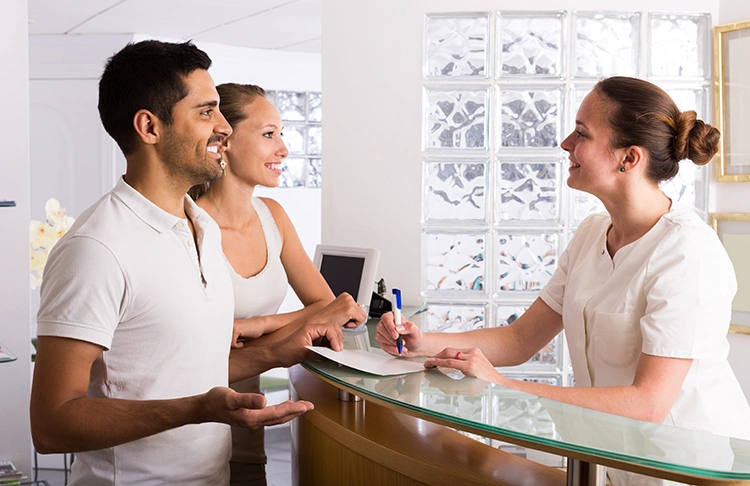 Smiling couple speaking with receptionist at Manchester Private Hospital during check-in