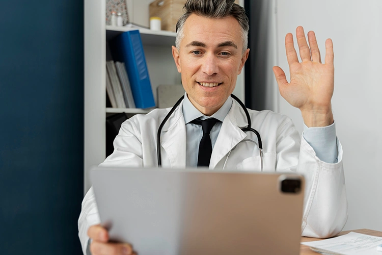 Male surgeon greeting patient during online video consultation 