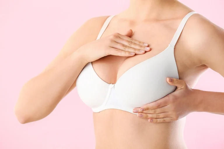 Close-up of patient wearing a support bra performing a gentle breast check after augmentation