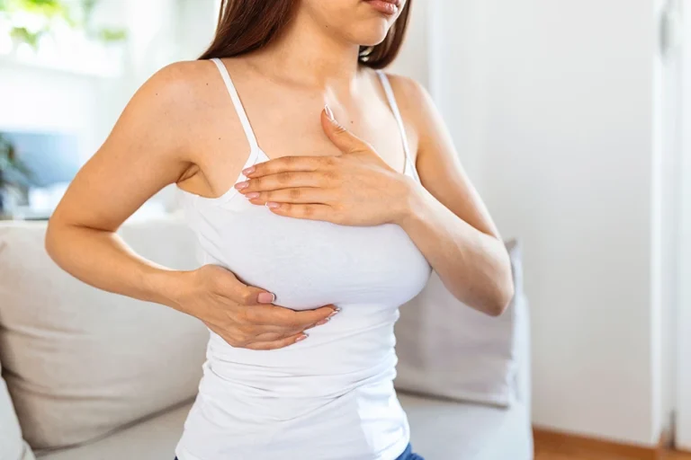 Woman holding her breast during a breast examination consultation for breast reduction surgery