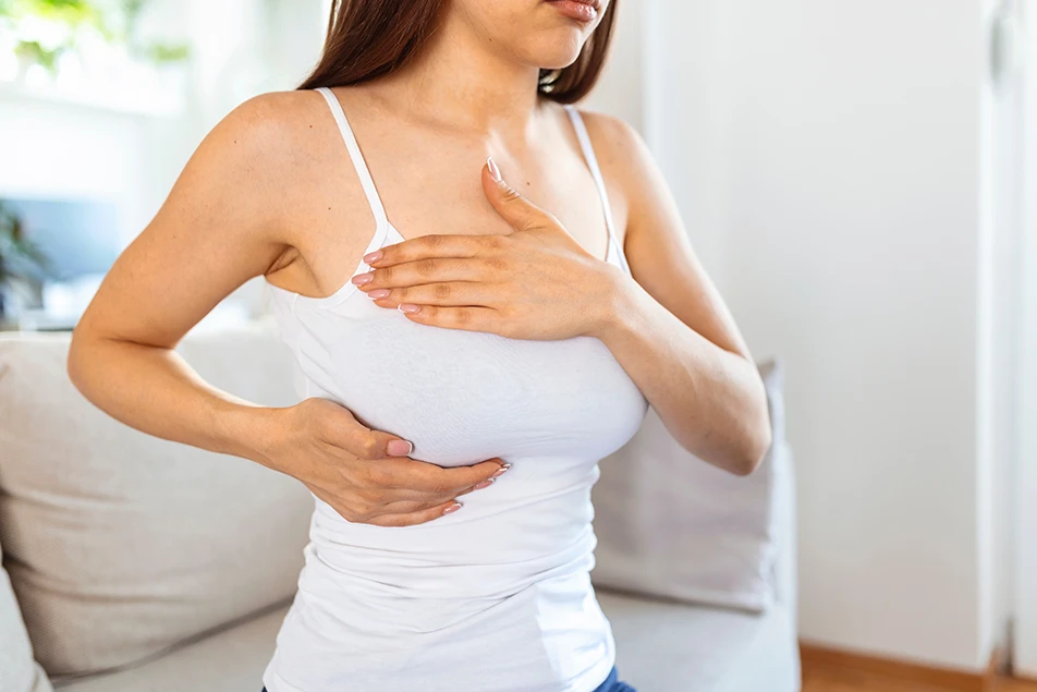 Woman holding her breast during a breast examination consultation for breast reduction surgery
